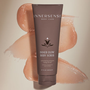 Tube of Innersense Inner Glow Body Scrub with swatch of peach coloured scrub behind it