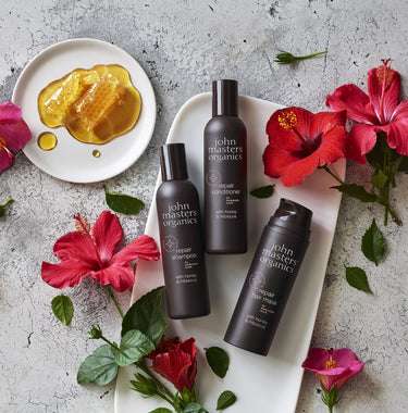 Flat lay of John Masters repair range with honey and flowers