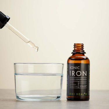 Drops of Kiki Health Ionic Iron Liquid Concentrate being added to a glass of water