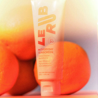 Le Rub Everyday Sunscreen SPF30 tube with lifestyle imagery and oranges