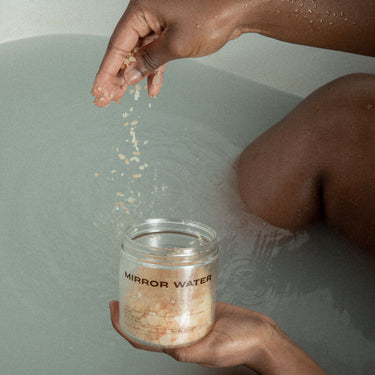 Model in the bath dropping the salts from Mirror Water Bathing Ritual Set into the water