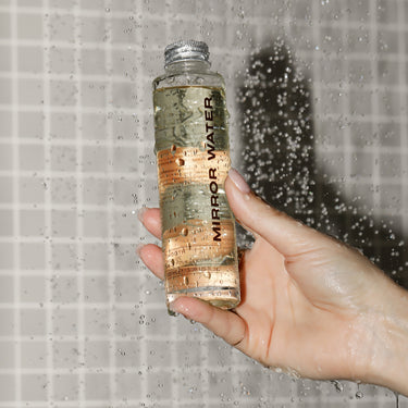 Bottle of Mirror Water Buff & Smooth Set being held up in a shower