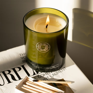 Close up of Mirror Water Bathing Ritual Set with flame burning sitting on top of a stack of magazines